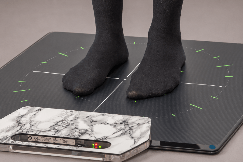 Person steht auf einer digitalen Pedografie-Messplatte zur Analyse der Druckverteilung der Füße.